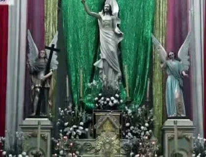 El altar mayor de la parroquia entre ángeles, flores y cortinas verdes